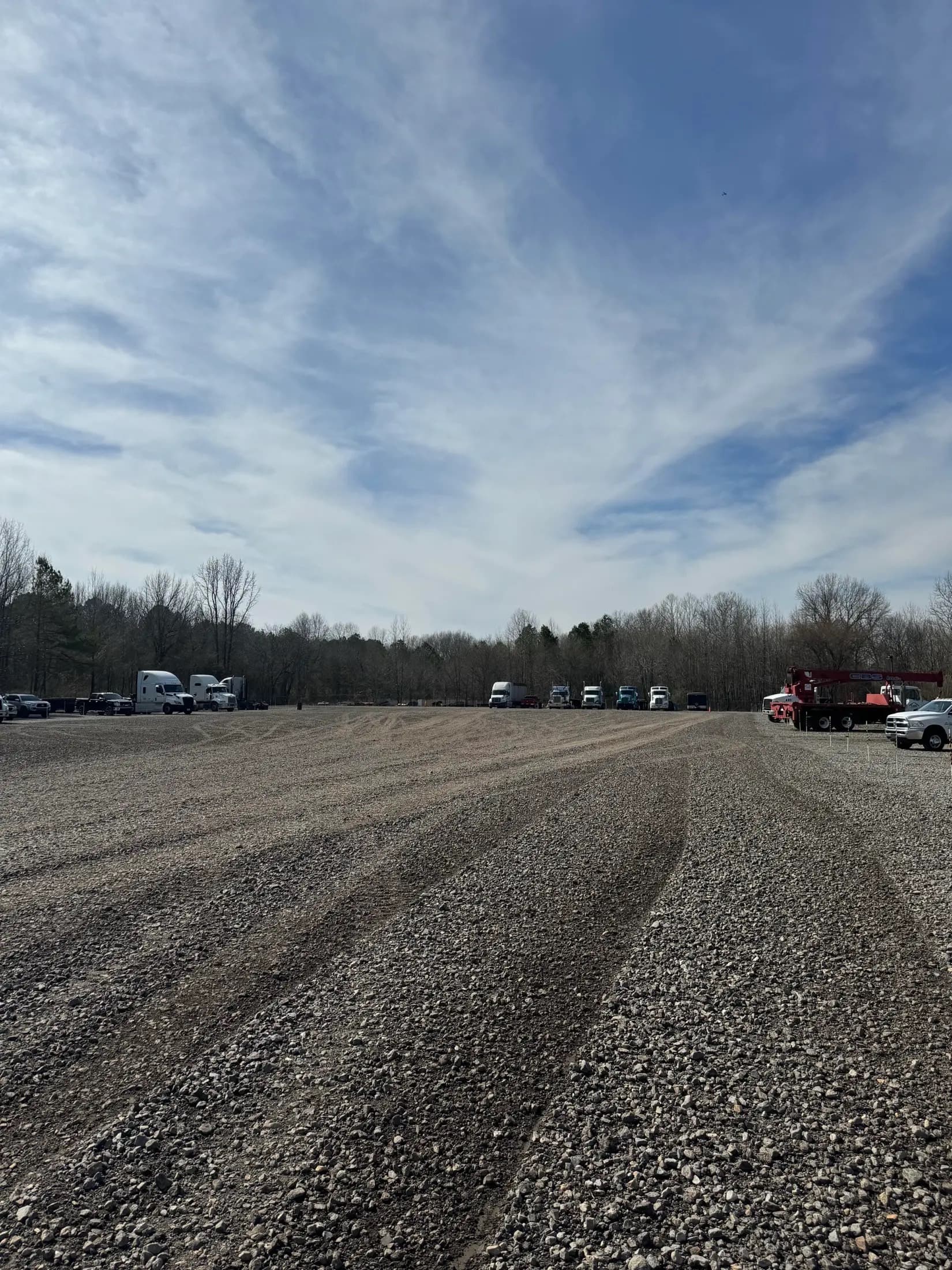 Graveled yard at MidArk Outside Storage with semi trucks parked along the tree line